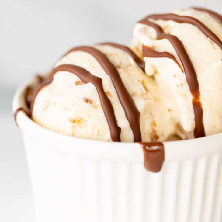 A white ramekin filled with vanilla ice cream and covered with dripping chocolate homemade magic shell.