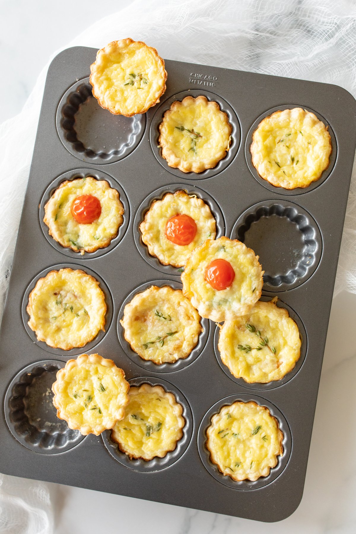A variety of mini cheese tarts on a muffin tin.