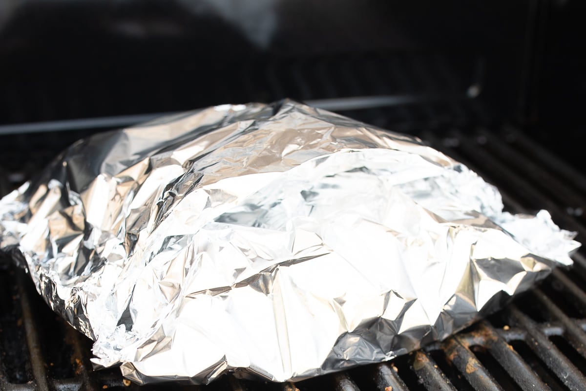 Salmon inside aluminum foil on a grill.