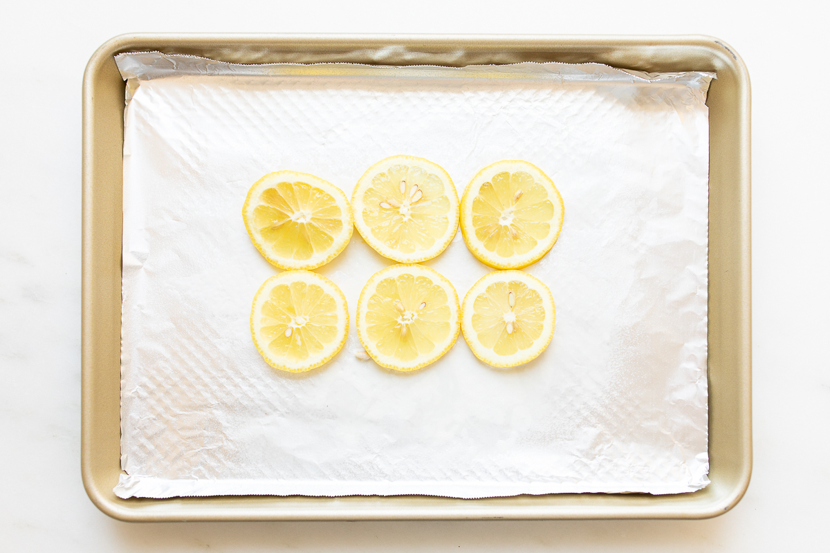 Sliced lemons on a foil lined baking sheet.