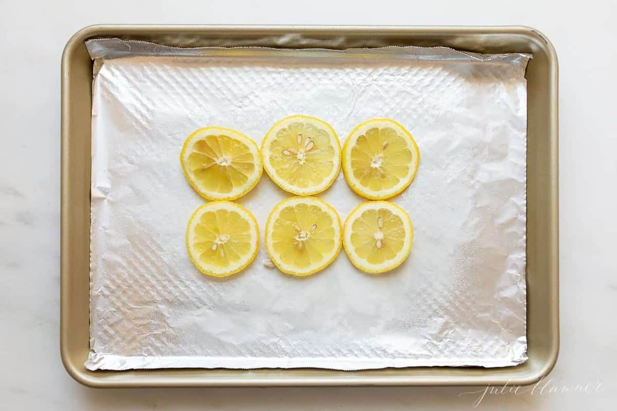 A baking sheet with a slice of aluminum foil with slices of lemon