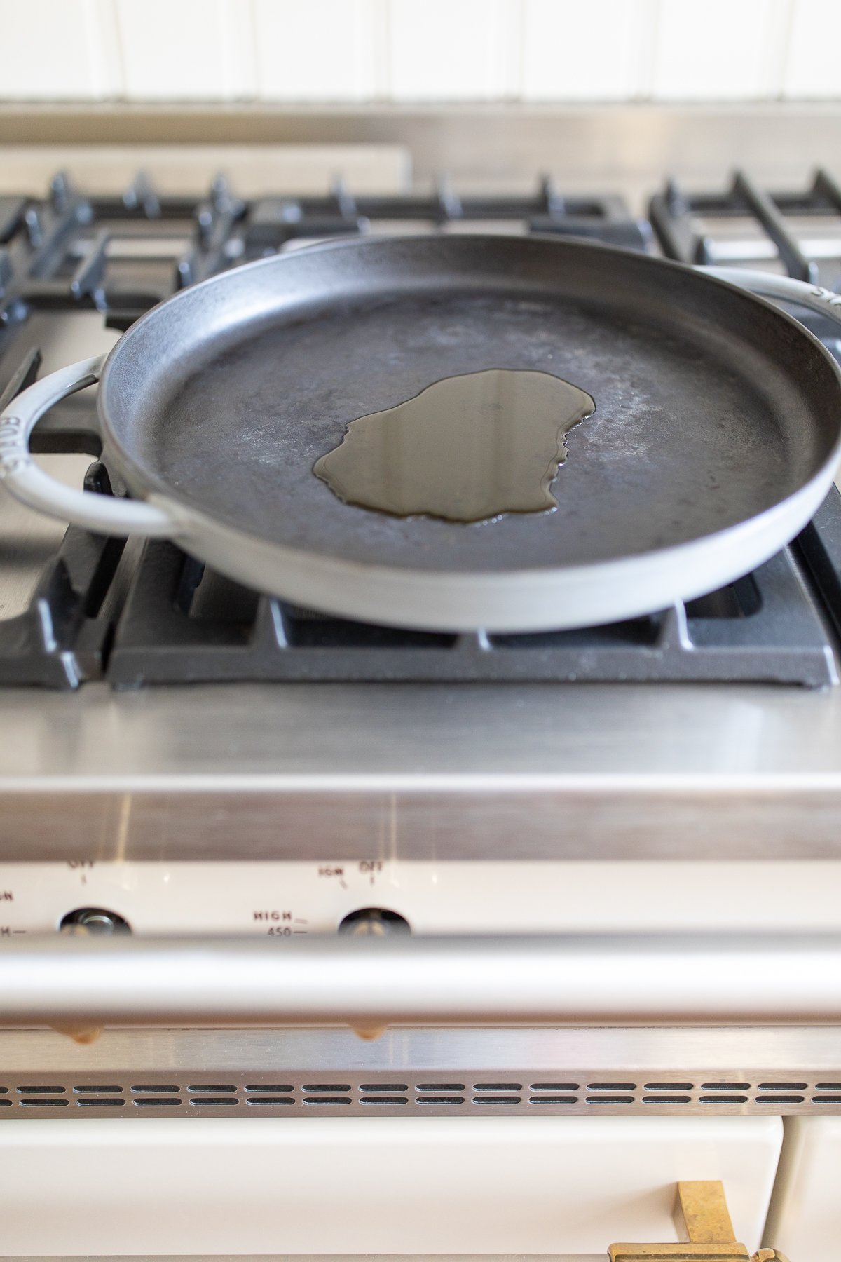 A cast iron skillet with a little oil on a stovetop.