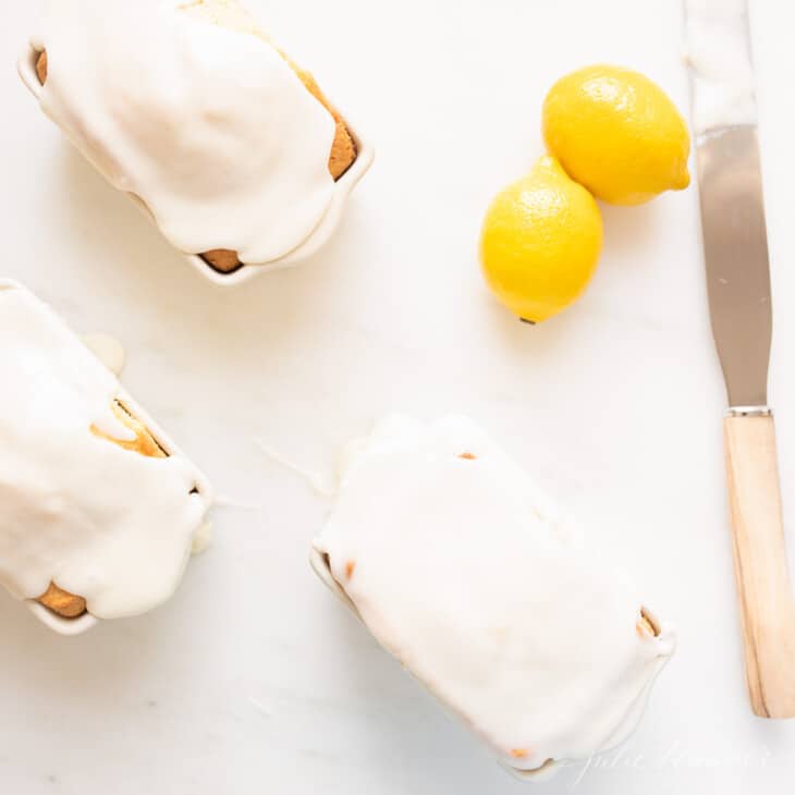 lemon glaze on miniature cakes with lemons and spatula