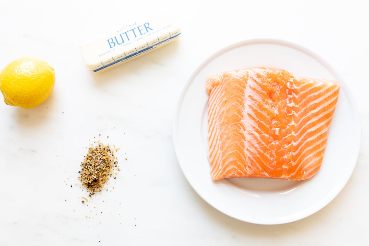 Ingredients for lemon pepper salmon laid out on a marble countertop.