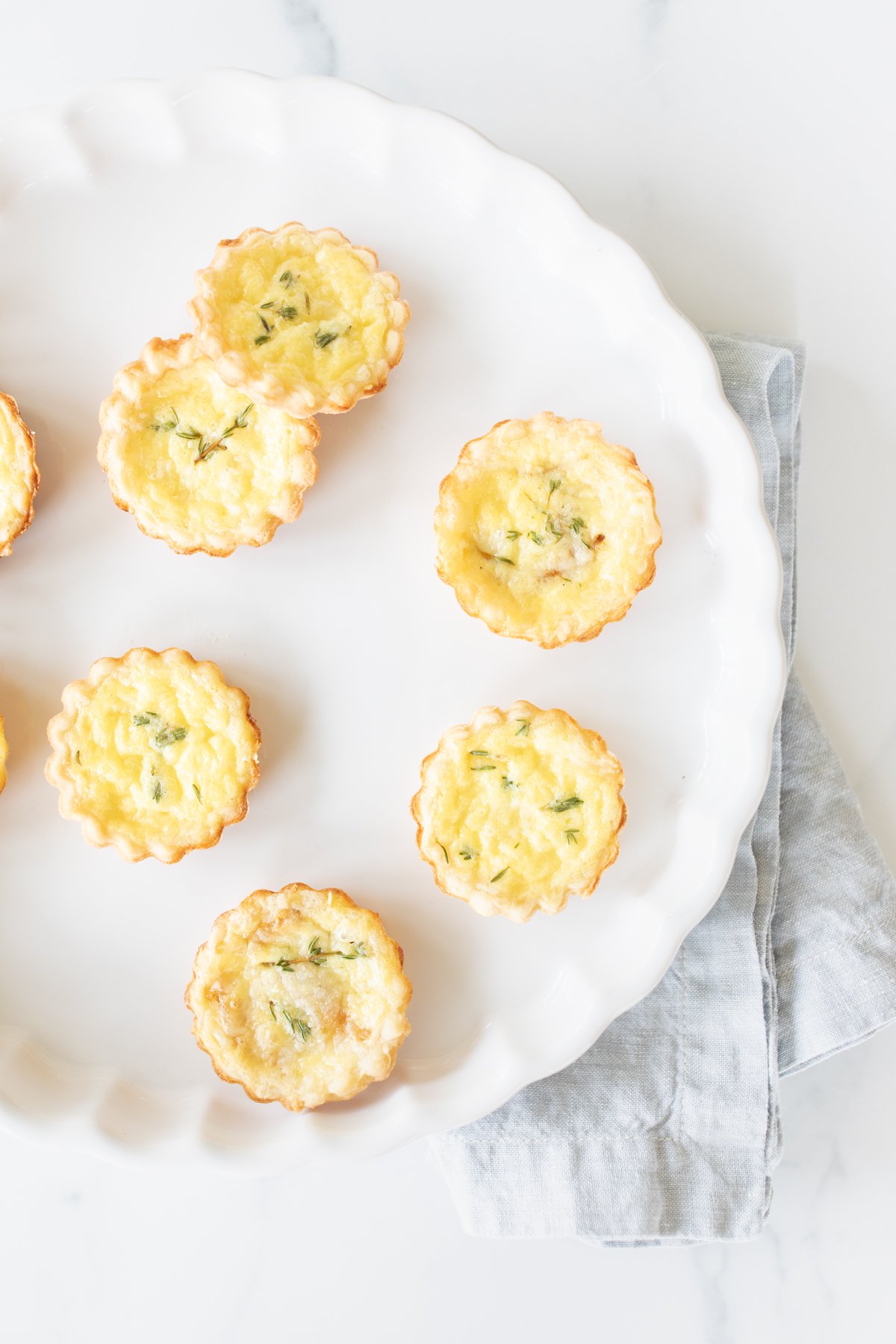 Mini cheese tarts on a white platter. 