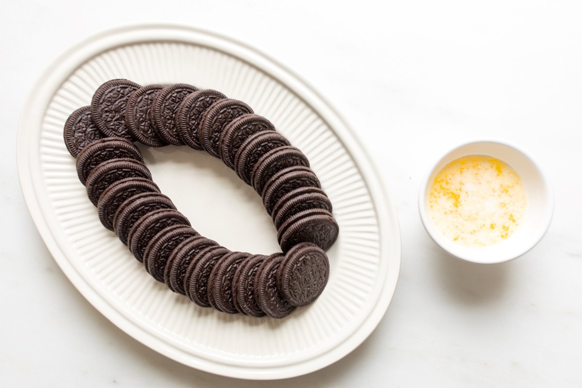 A white platter full of oreos and a bowl of butter to the side.