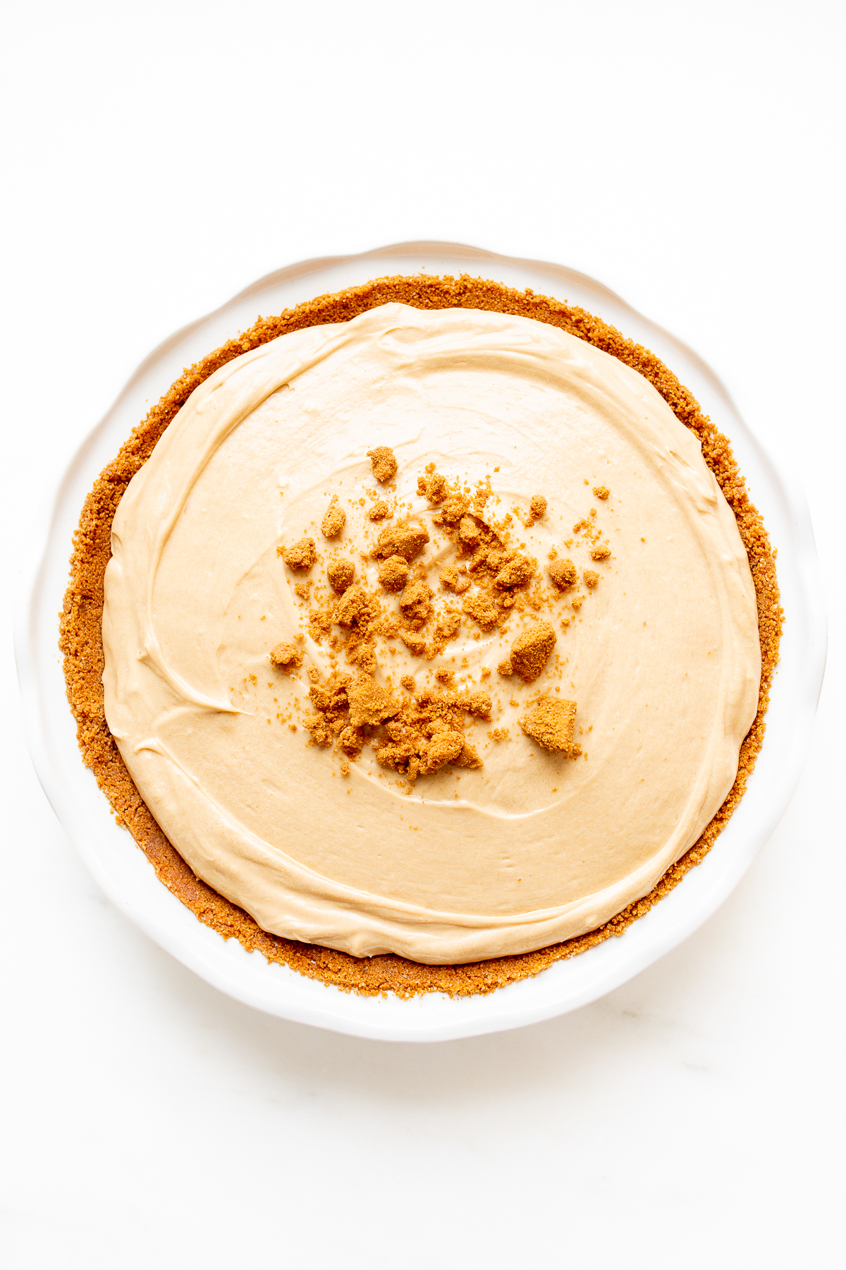 A cookie butter pie on a white marble countertop. 