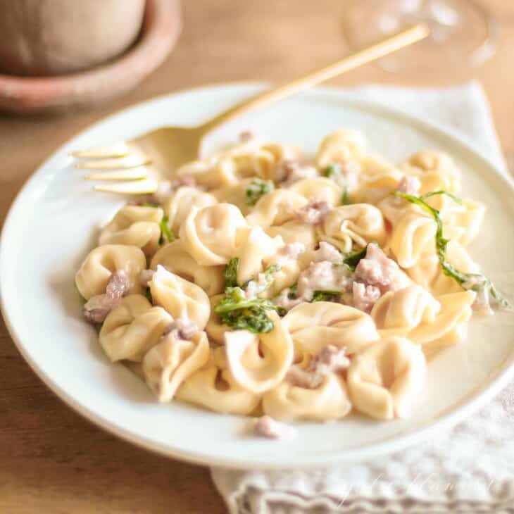 tortellacci on white plate with gold fork