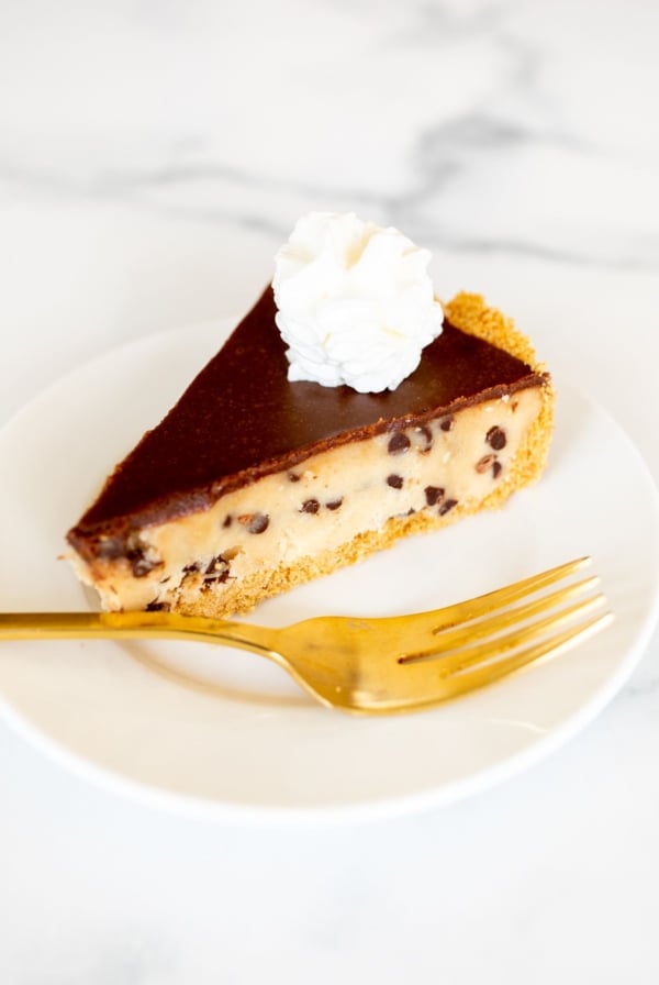 A white plate with a slice of cookie dough pie and a gold fork.