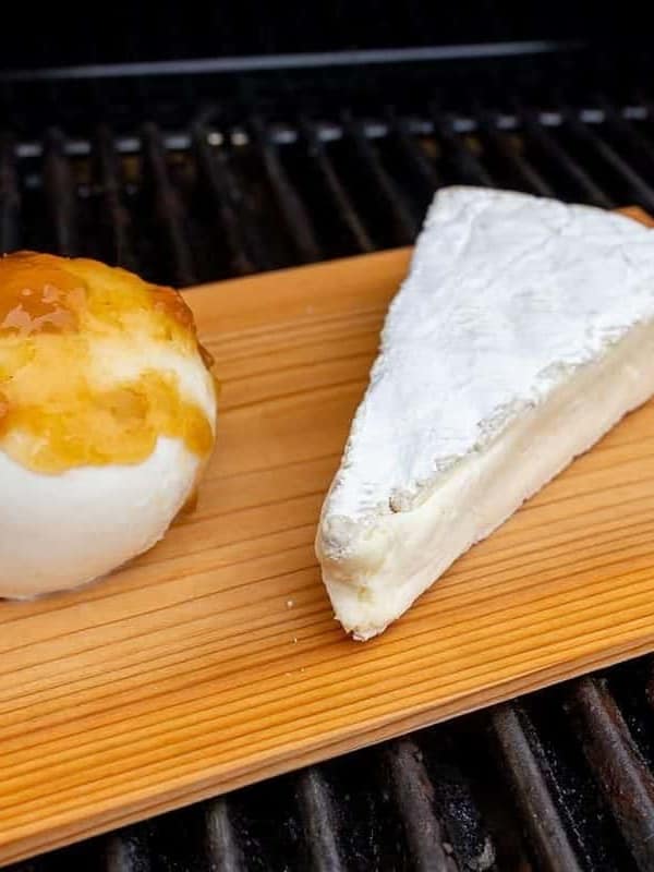 Grilled mozzarella and brie on a wooden cutting board.