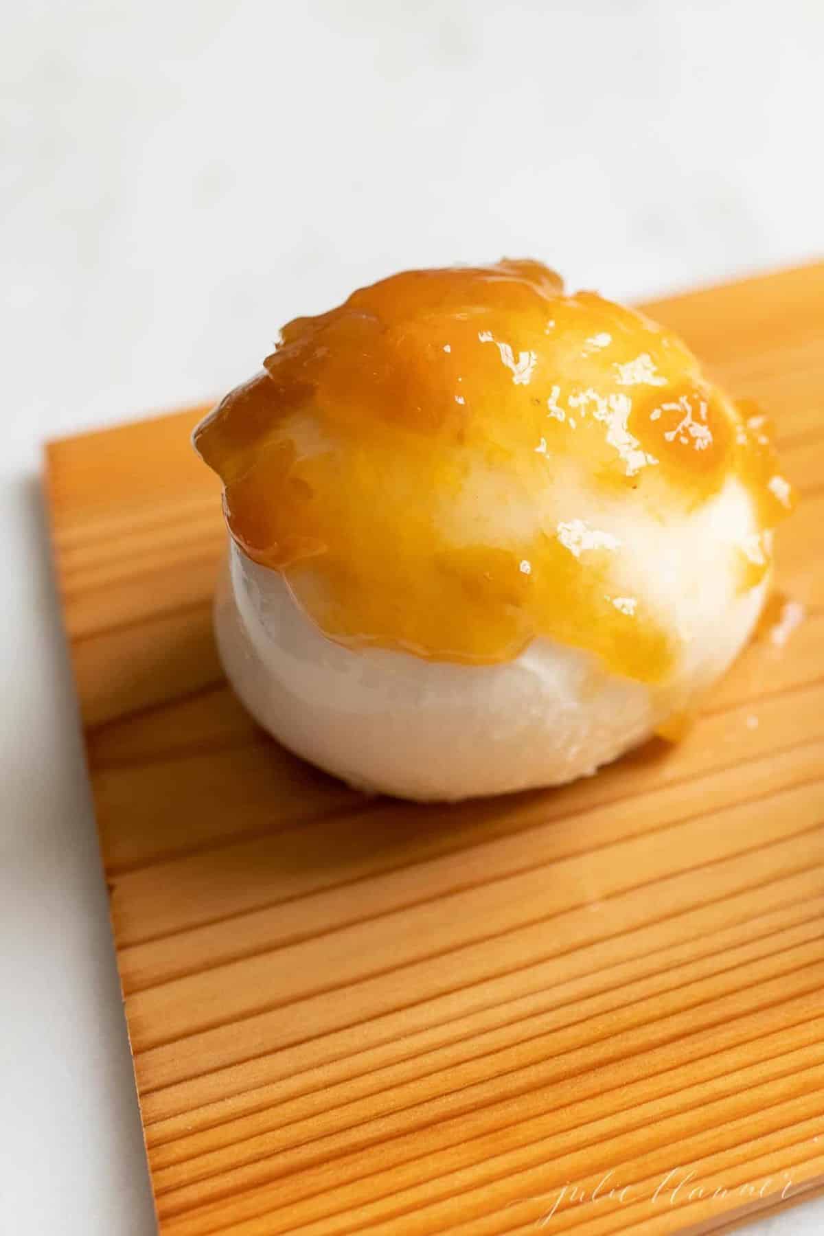 A grilled mozzarella appetizer covered in peach preserved on a cedar plank.
