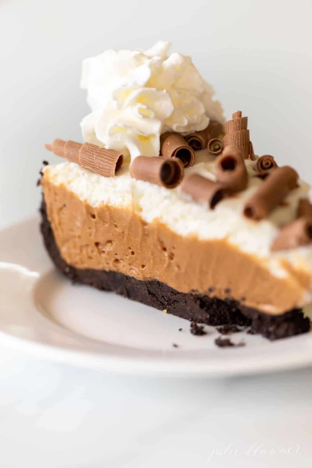A slice of french silk pie in a chocolate pie crust on a white plate.