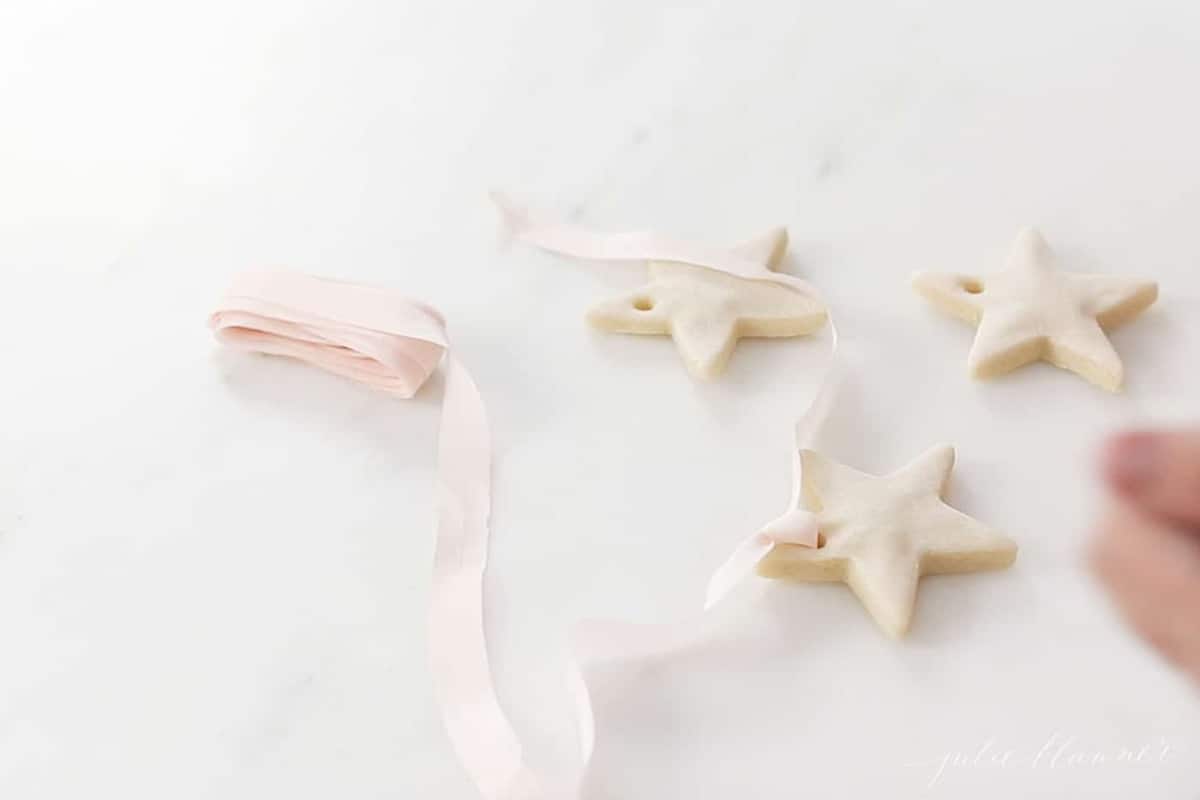 A marble surface with salt dough star ornaments and a blush pink ribbon.