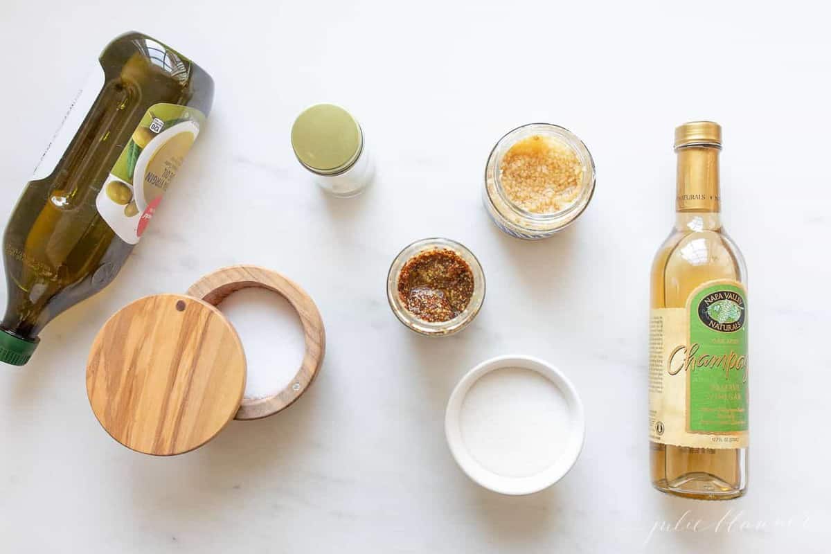 A marble surface with a spread of ingredients to make a homemade vinaigrette recipe.