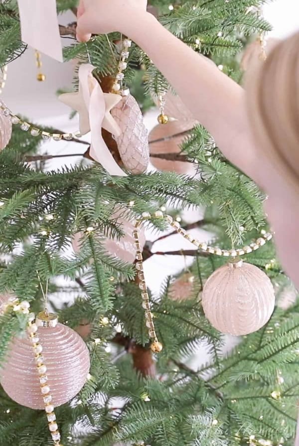 The edge of a little girl's face and hands as she places homemade salt dough ornaments on a Christmas tree.