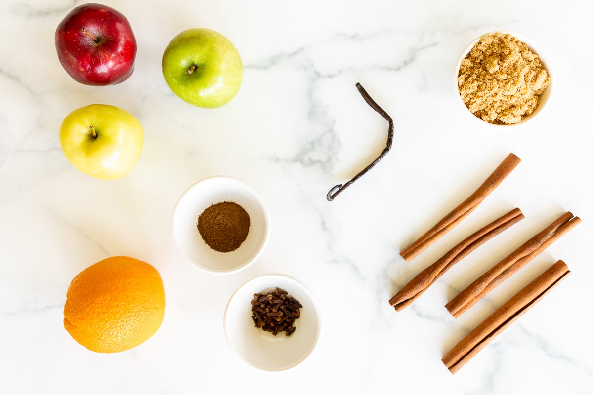 ingredients for a homemade apple cider recipe on a marble countertop