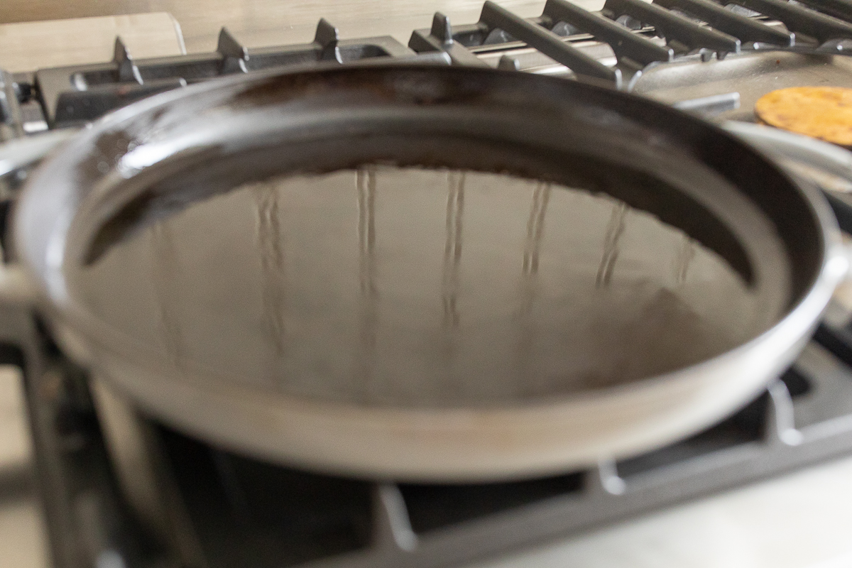 A cast iron skillet with oil inside, on a stovetop.
