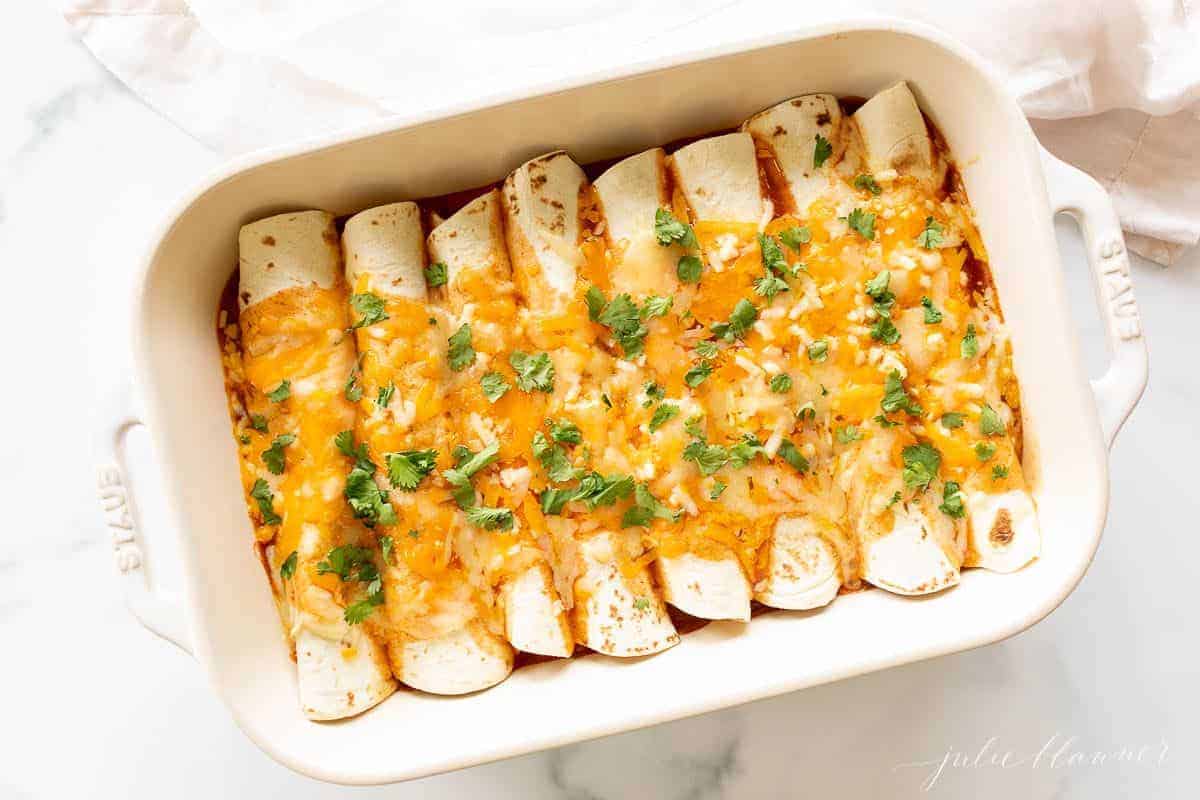 A white casserole dish filled with an easy chicken enchilada recipe.
