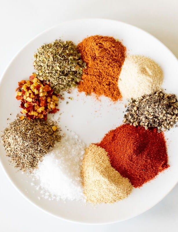 A white plate with piles of spices to make cajun seasoning.