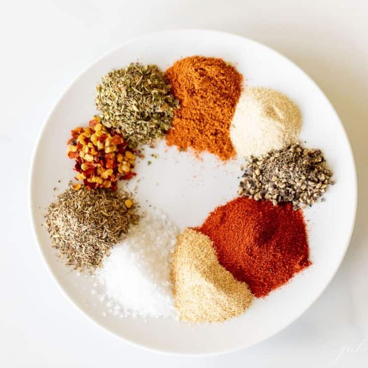 A white plate with piles of spices to make cajun seasoning.