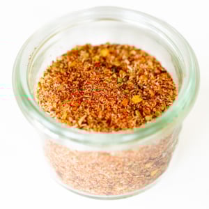 A small glass jar full of cajun seasoning.