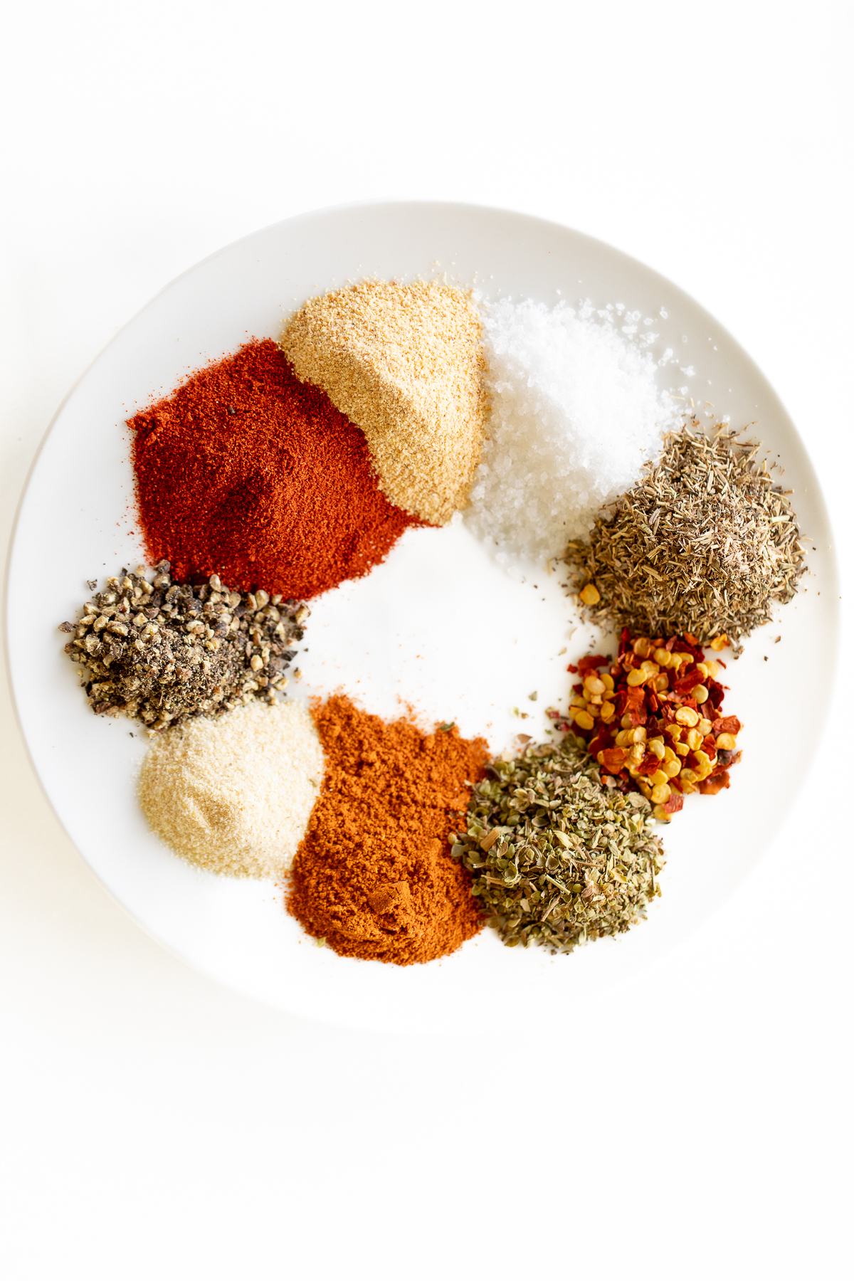 Various spices on a white plate for a homemade cajun seasoning recipe.