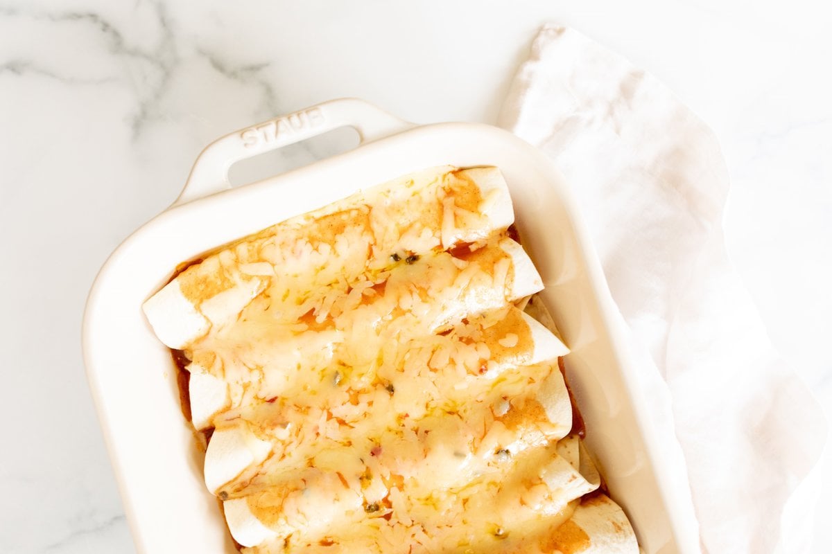 A white baking dish filled with fresh cheese enchiladas.