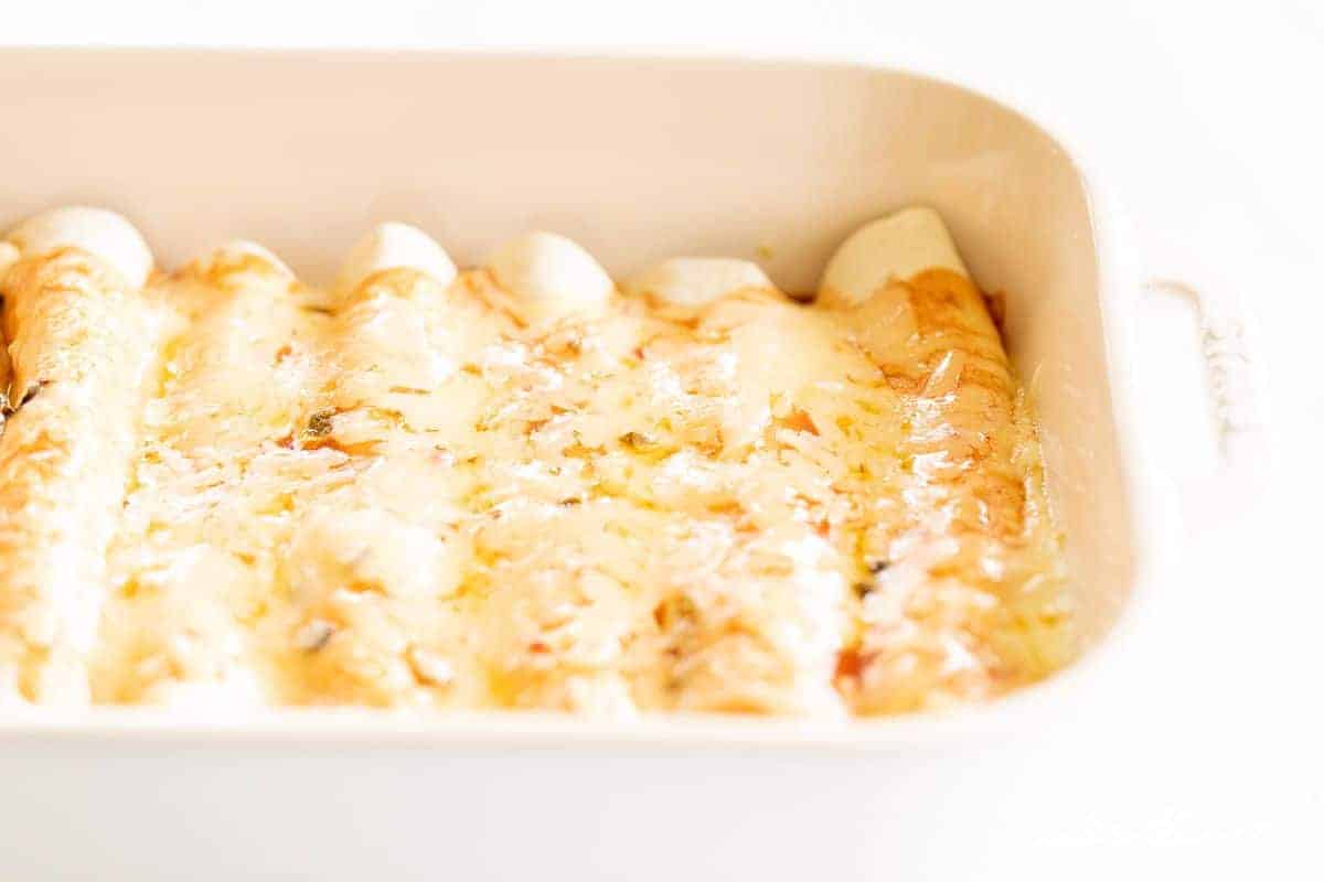 A white casserole dish filled with a cheese enchilada recipe.