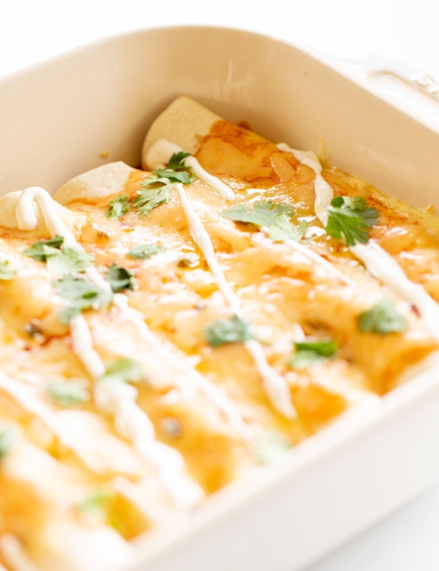 A white baking dish filled with fresh cheese enchiladas.