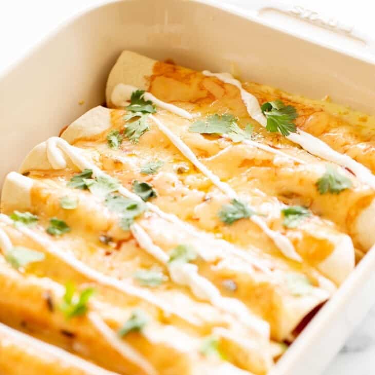 A white casserole dish filled with a cheese enchilada recipe.