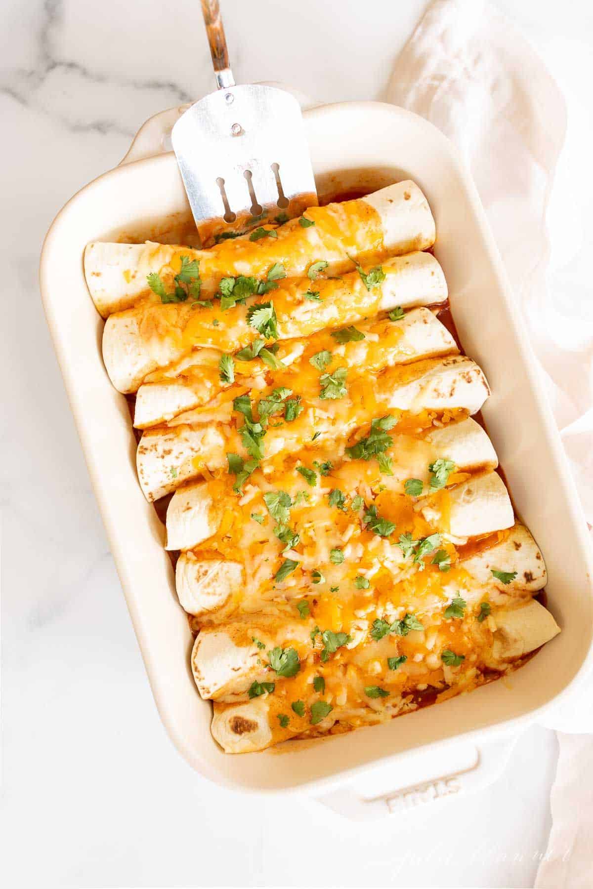 A white casserole dish filled with a chicken enchilada recipe.