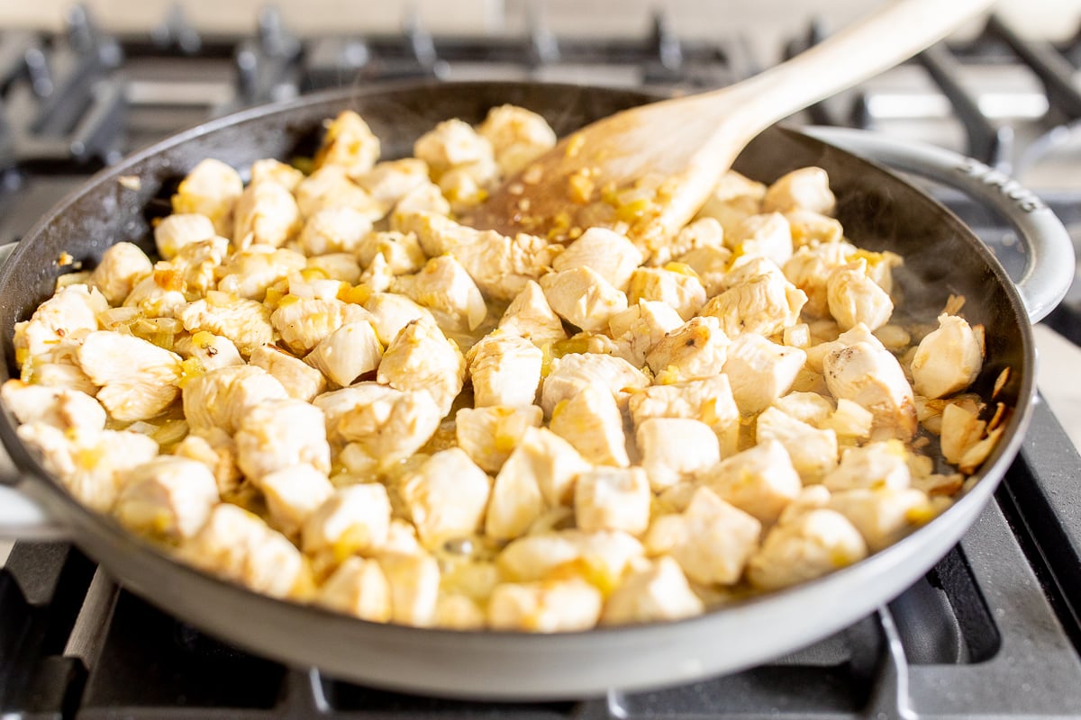Small pieces of chicken cooking in a cast iron skillet