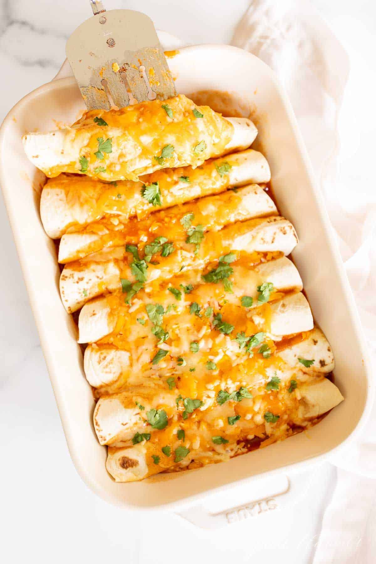 A white casserole dish filled with a chicken enchilada recipe.