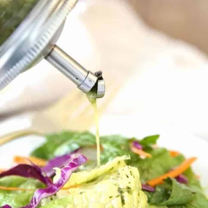 A mason jar full of cilantro lime vinaigrette being poured onto a salad