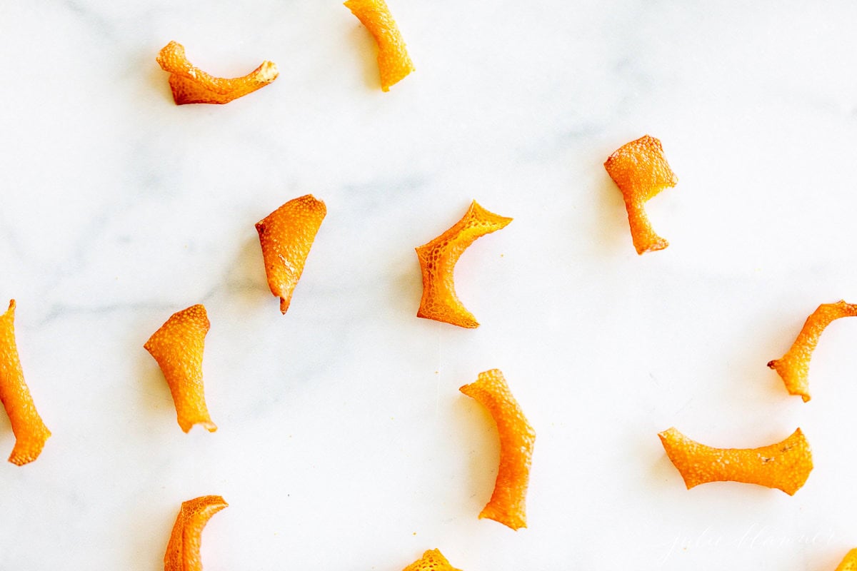Scattered pieces of dried orange peel on a white marble surface.