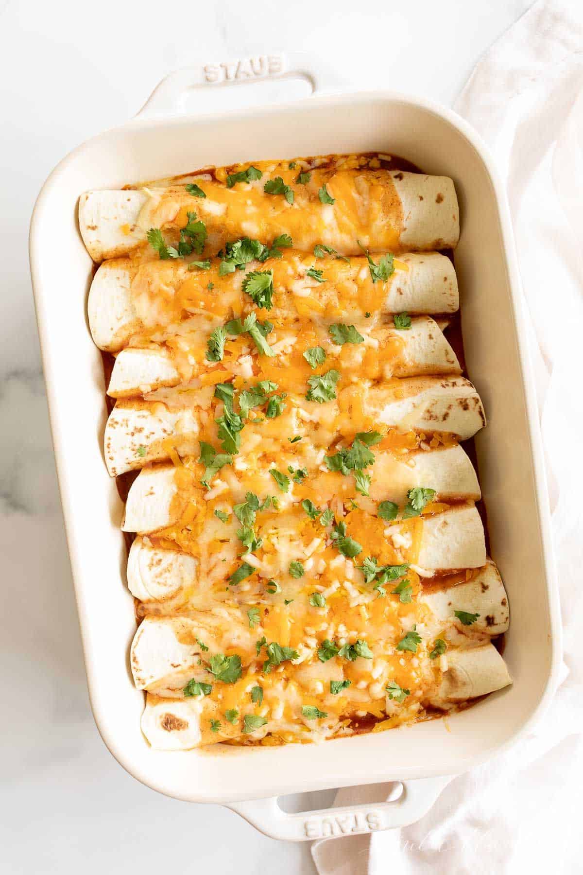 A white casserole dish filled with an easy chicken enchilada recipe.