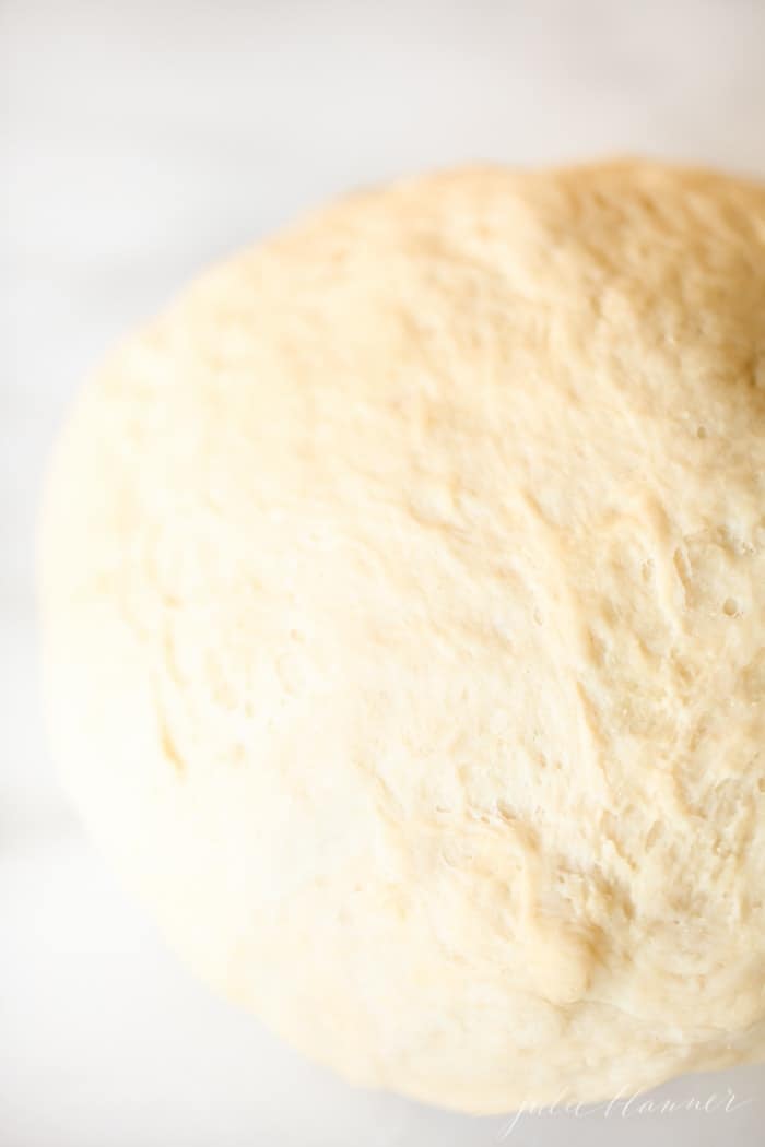 A big slab of dough for easy dinner rolls on a marble surface.