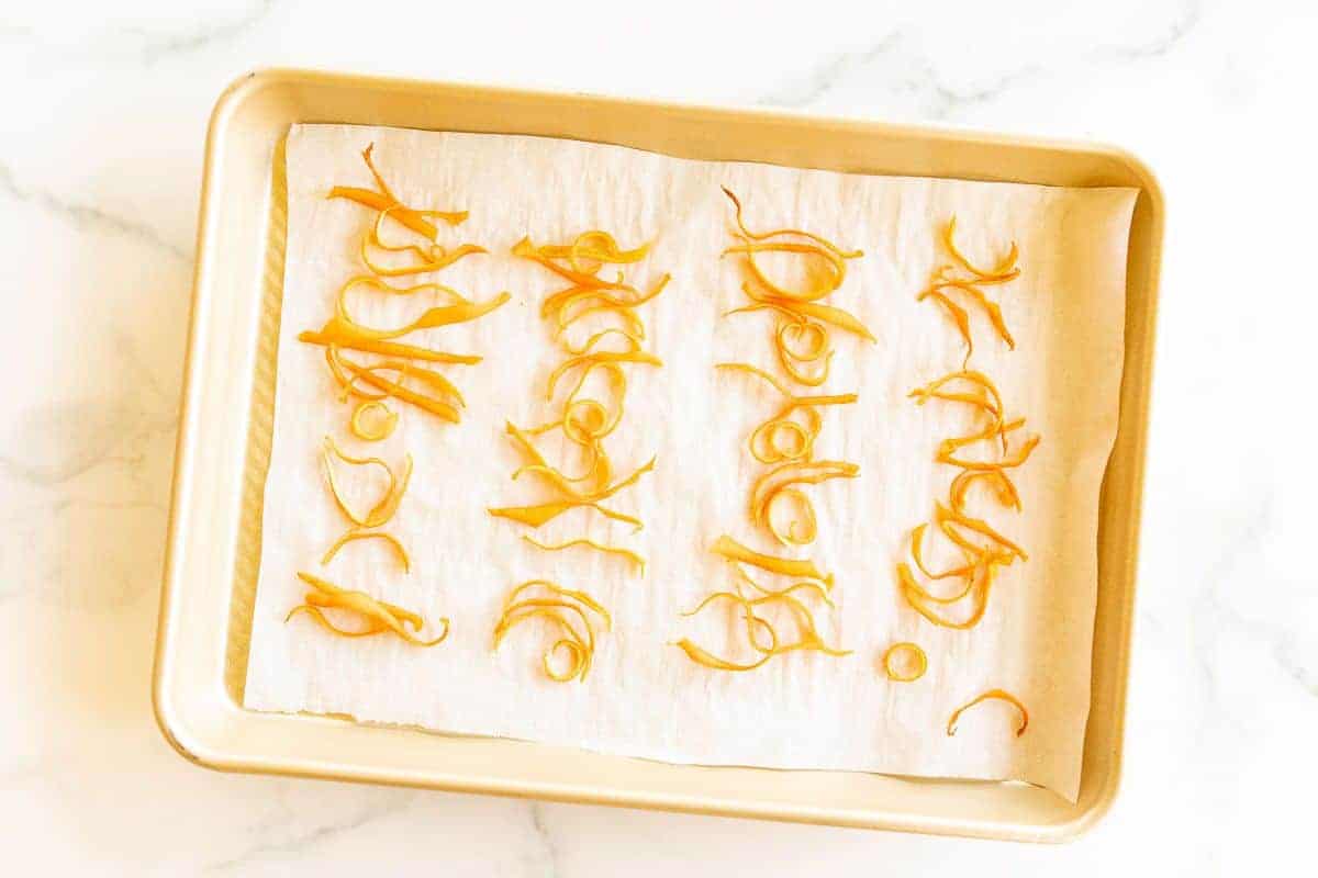 A gold sheet pan lined with parchment paper and covered in dried orange peels.