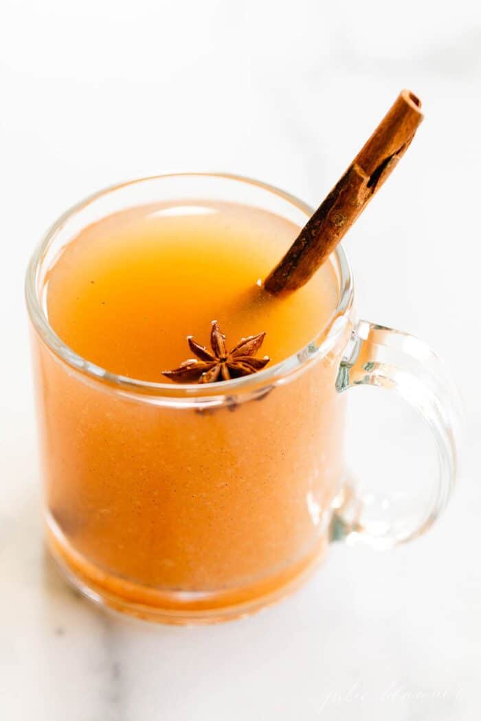 A single glass mug full of homemade pear cider, cinnamon stick for garnish.