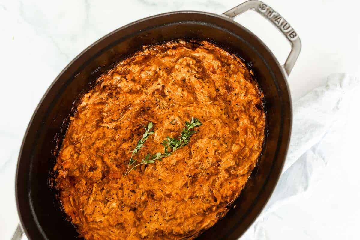 An oval cast iron coquette filled with a pork ragu recipe.