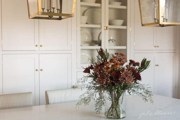 An al fresco table set with a fall centerpiece and candles.