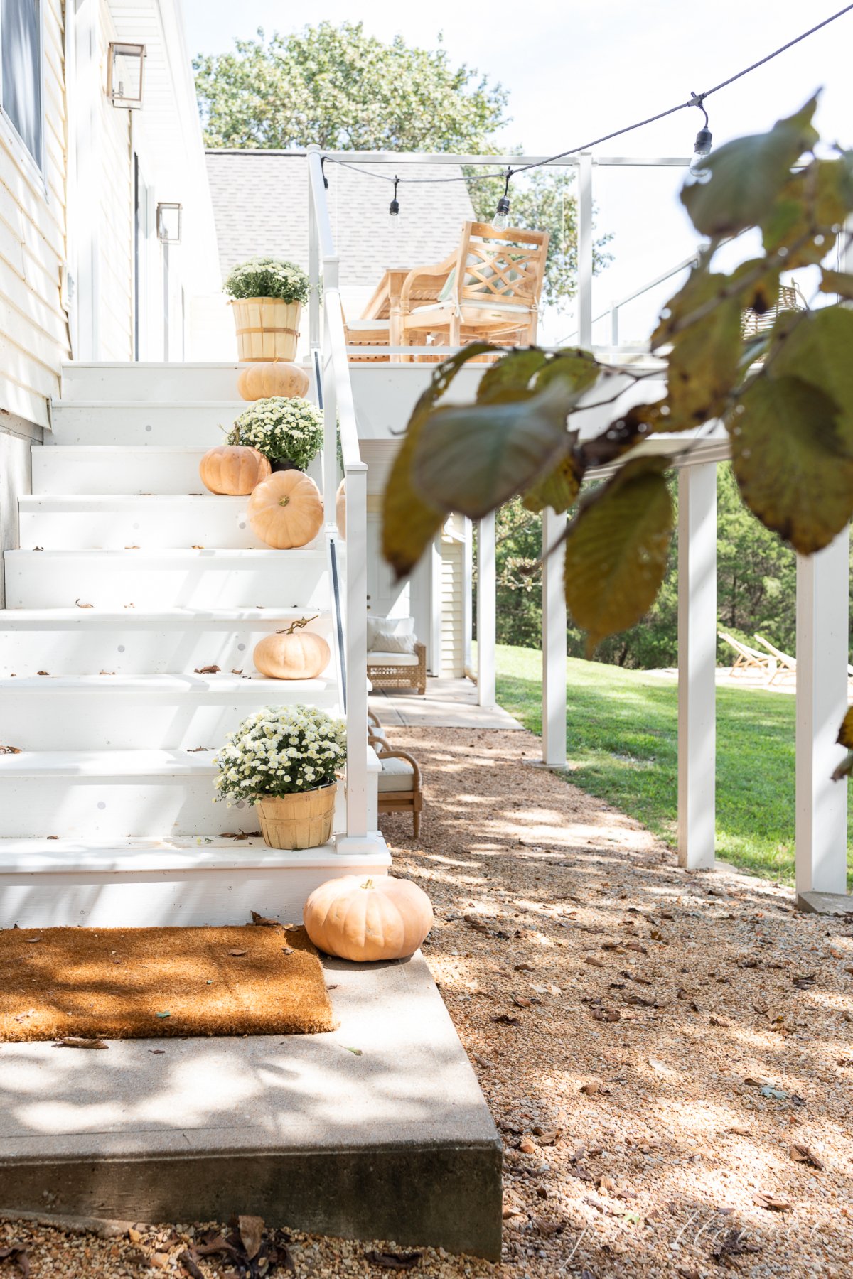 Fall porch decor on white steps, with pumpkins and mums down the steps.