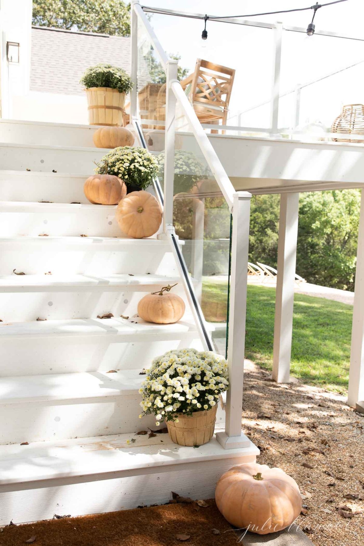 Fall porch decor on white steps, with pumpkins and mums down the steps.