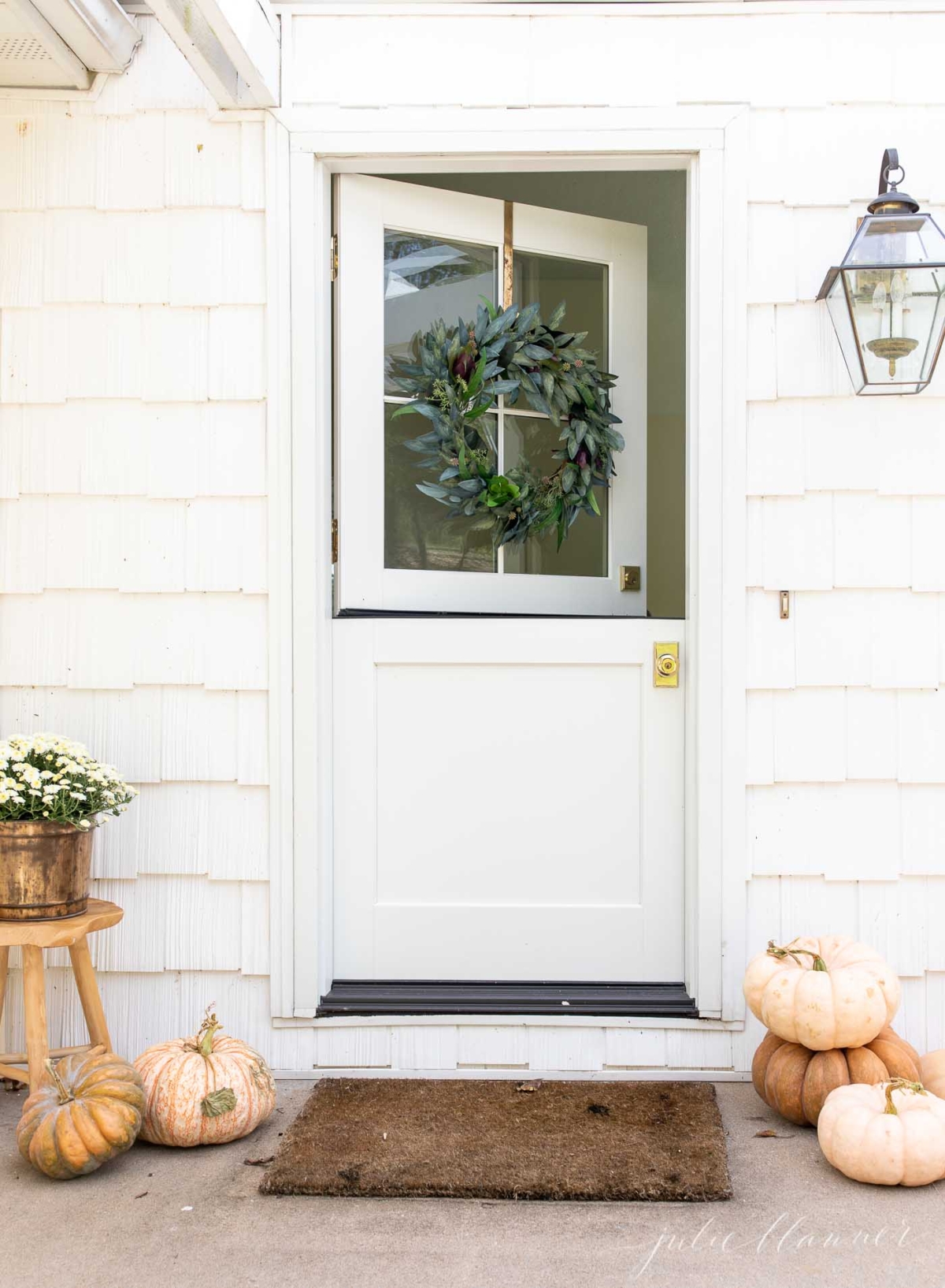 Fall porch decor with peach heirloom pumpkins, and a fall wreath on a Dutch door.