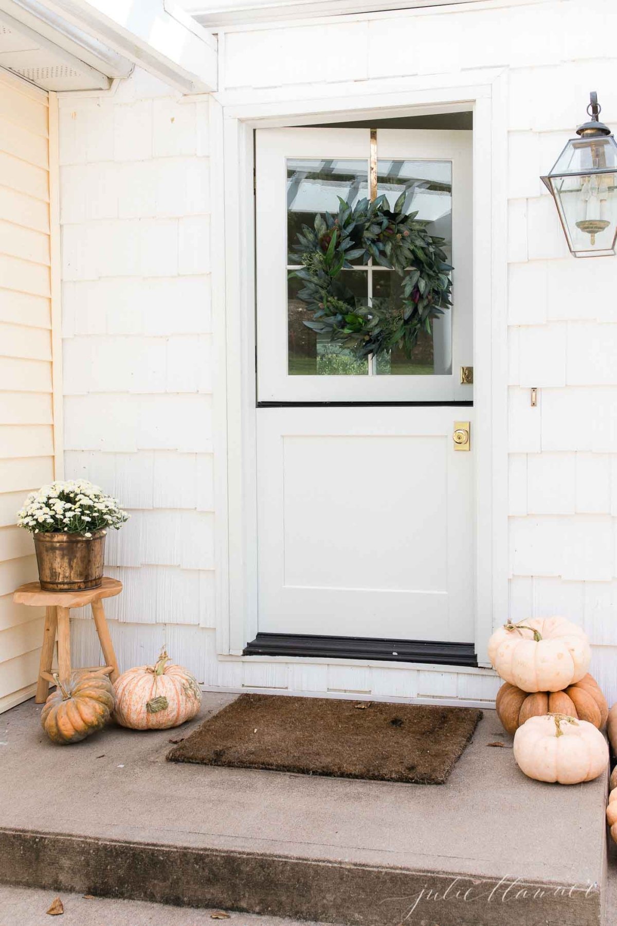 Fall porch decor with peach heirloom pumpkins, and a fall wreath on a Dutch door.