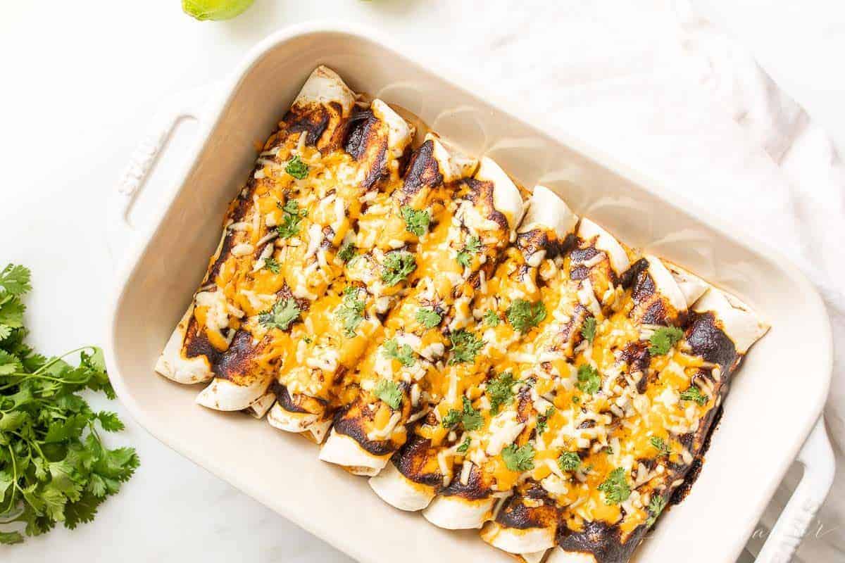 A white baking dish filled with ground beef enchiladas.