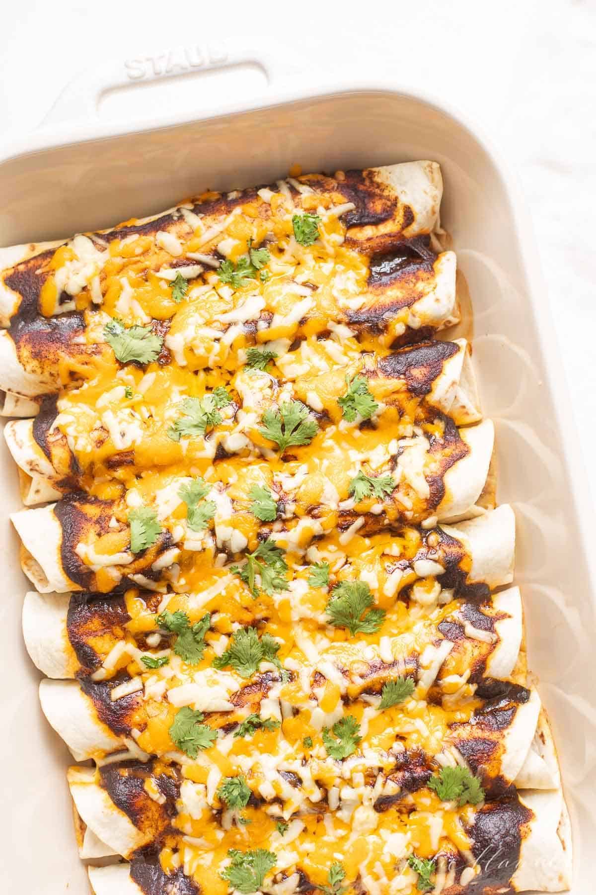 A ground beef enchilada recipe in a white baking dish.