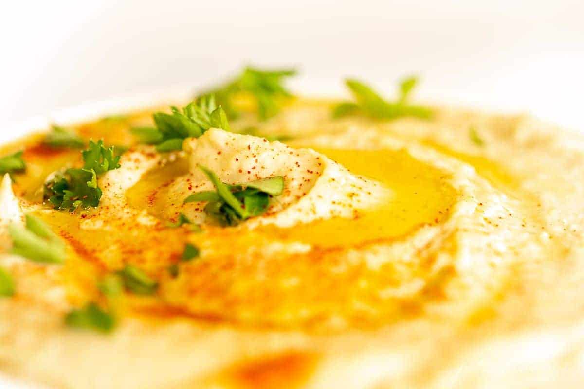 Close up shot of hummus swirled in a bowl with olive oil on top