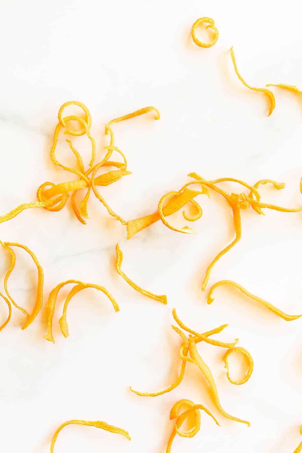 A marble surface with curls of dried orange zest.