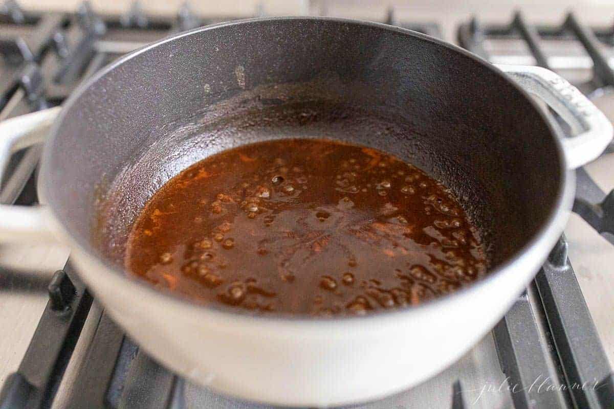 Looking into a cast iron pot full of a homemade enchilada sauce recipe on a stove top.